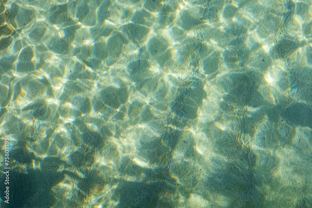 Fototapeta premium Sunlight dances on the clear water of the sea, creating a beautiful sparkle.