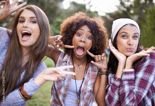 Funny face, portrait and friends in a park with silly, fun or bonding on vacation, weekend or reunion in nature. Crazy, expression and gen z women in a forest with goofy, comic or joke and gesture photo