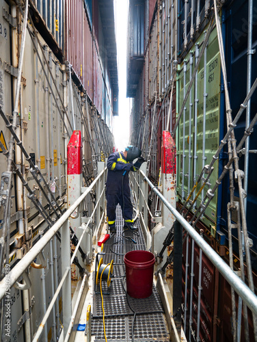Seaman crew member fitter welder of cargo vessel is repairing ship structure lashing bridge by welding of new pipes dressed with proper ppe