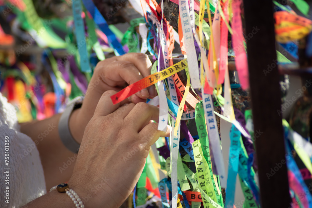 Obraz premium A Catholic faithful is seen tying a souvenir ribbon on the railing of the Senhor do Bonfim church in the city of Salvador, Bahia.