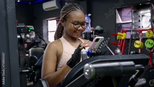 Young black woman in the gym using smartphone