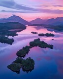 A serene aerial snapshot of Loch Hena Tiko at sunset, showcasing Scotland's misty mountains, pastel skies, and tranquil waters with verdant isles.