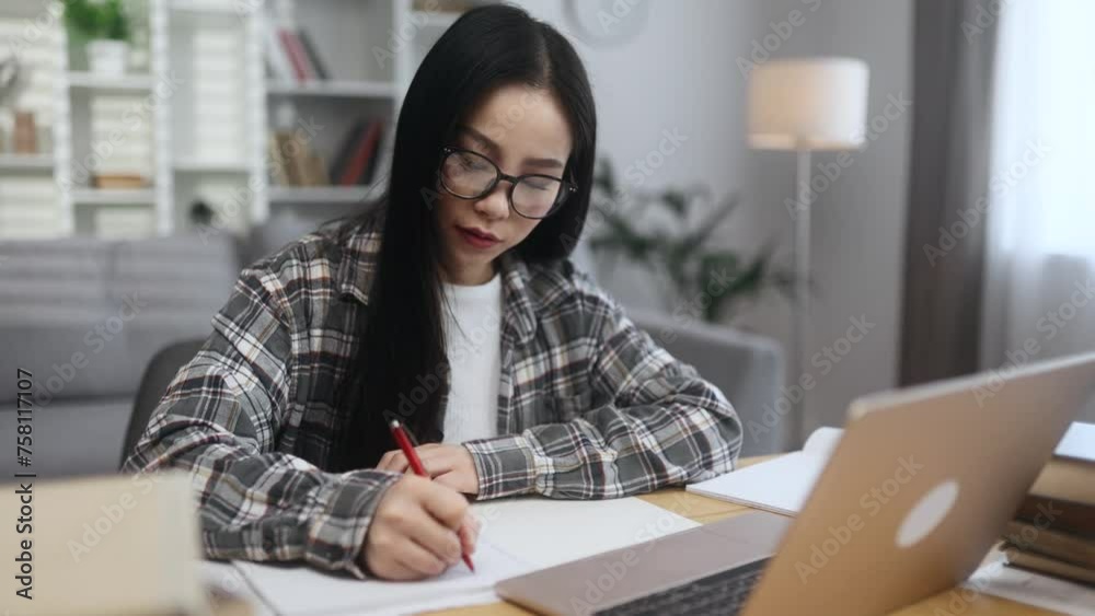 Charming asian girl preparing for exam at university studying at home workplace Pretty student make notes while looking at laptop computer listening lesson indoors Distance remote education Charming asian girl preparing for exam at university studying at home workplace Pretty student make notes while looking at laptop computer listening lesson indoors Distance remote education
