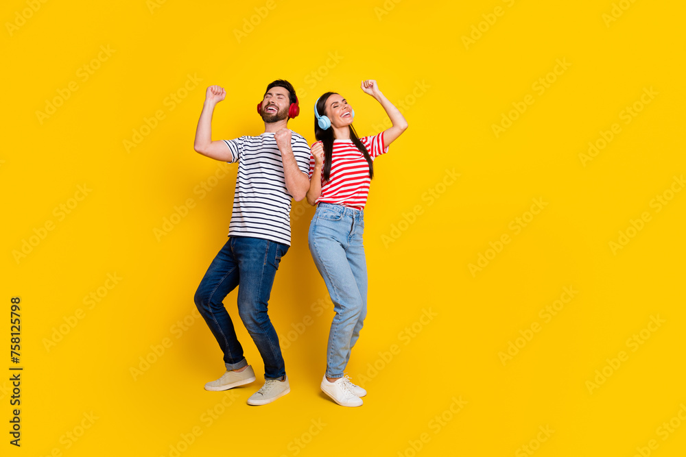 Full size photo of two carefree positive people listen music headphones dancing empty space isolated on yellow color background Full size photo of two carefree positive people listen music headphones dancing empty space isolated on yellow color background
