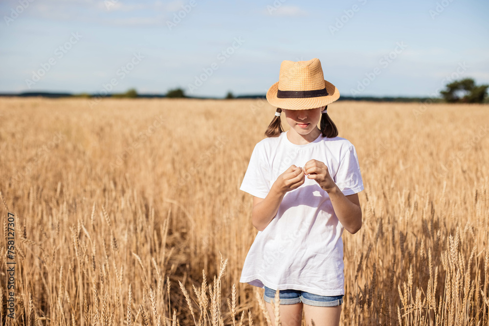 Close-up portrait of a beautiful teenage girl looking in surprise at a flower that she holds in ears in a field of wheat. Copy space Close-up portrait of a beautiful teenage girl looking in surprise at a flower that she holds in ears in a field of wheat. Copy space