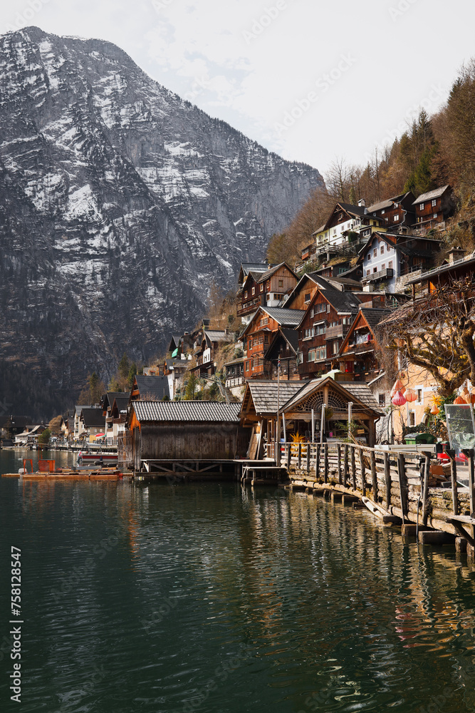 Fototapeta premium A beautiful view of Hallstatt, Austria, with the Alps in the background surrounding the village. The wooden alpine houses, along with the mountains reflecting in the lake
