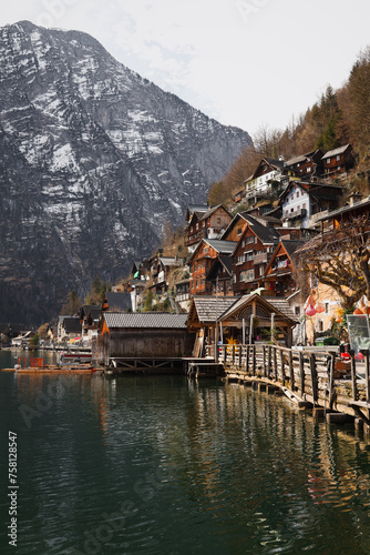 A beautiful view of Hallstatt, Austria, with the Alps in the background surrounding the village. The wooden alpine houses, along with the mountains reflecting in the lake