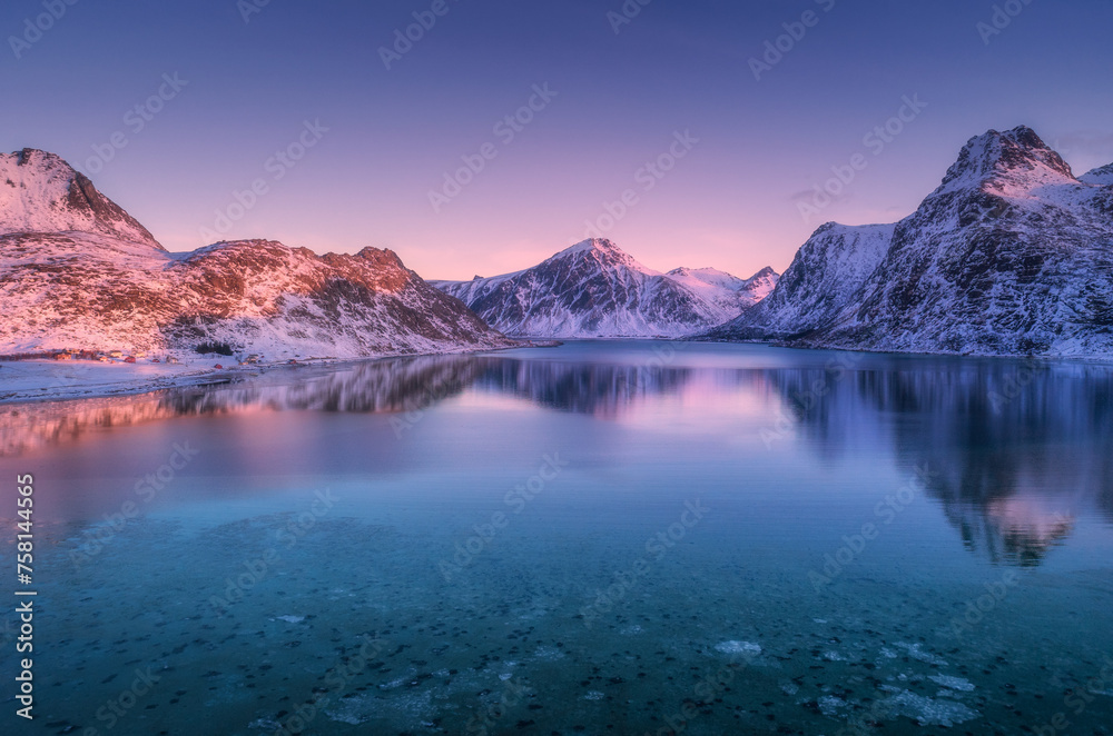 Aerial view of snow covered mountains and sea at colorful sunset