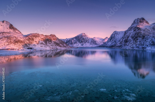 Aerial view of snow covered mountains and sea at colorful sunset © Qasim