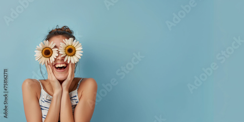 A woman laughs celebrating spring with two flowers in her eyes like glasses. Spring concept, banner, web, advertising.