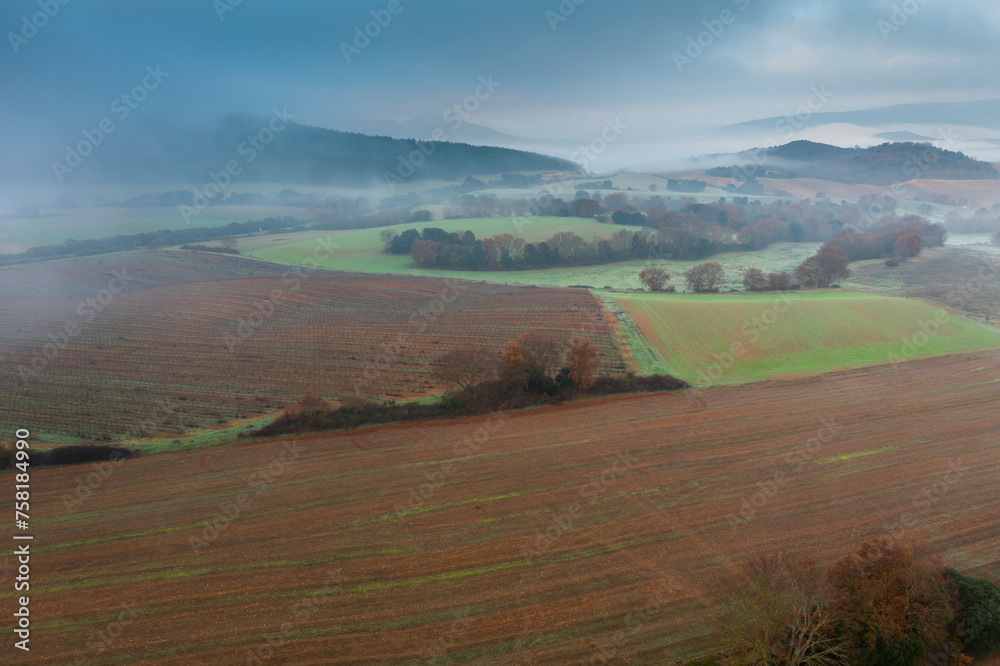 Aerial view of cultivated plots and hedges in autumn with fog.