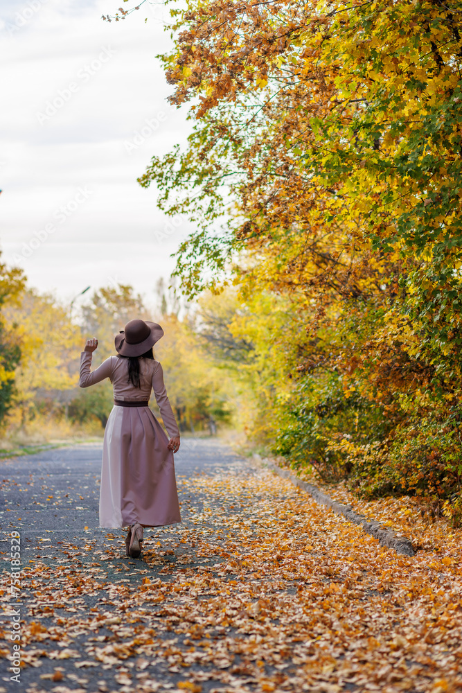 Young woman's contemplative walk amidst the leaf-covered walkway