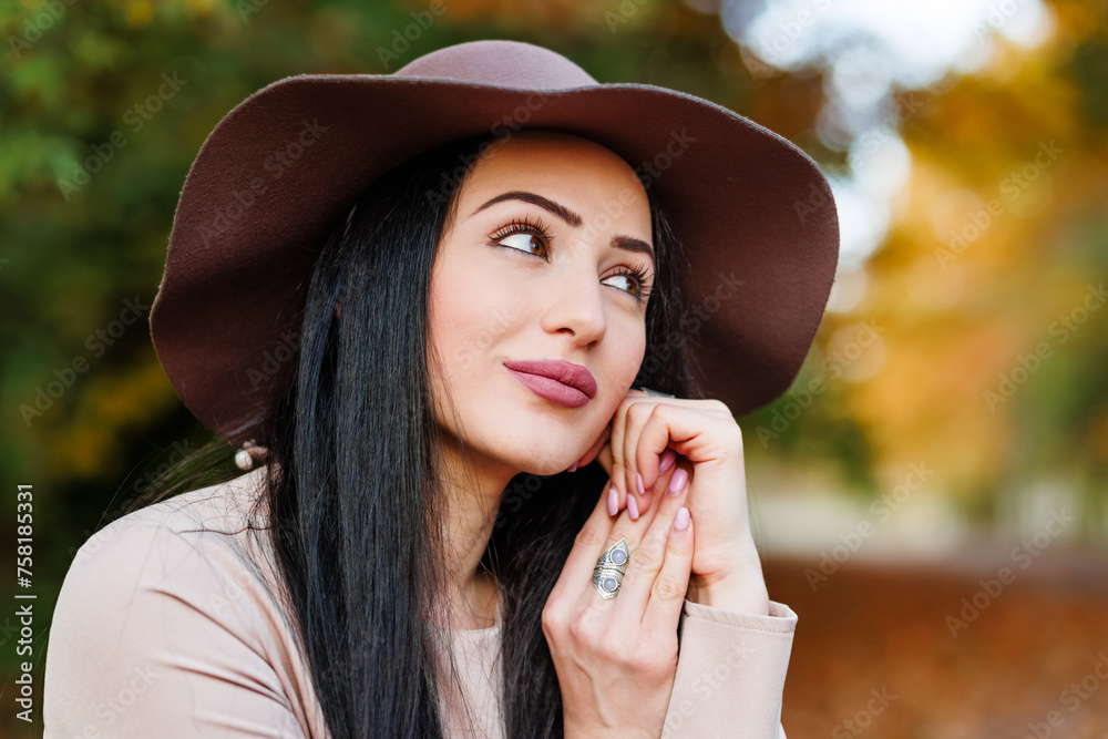 Closeup of young woman in a beige coat and hat enjoying the vibrant colors of the season.