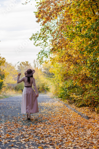Obraz na płótnie Young woman's contemplative walk amidst the leaf-covered walkway w salonie