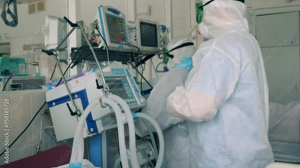 Medical equipment being regulated by doctors in covid-19 protection suits. Covid-19 hospital, coronavirus, medical, healthcare concept. Medical equipment being regulated by doctors in covid-19 protection suits. Covid-19 hospital, coronavirus, medical, healthcare concept.