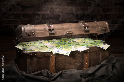 Vintage big treasure box filled with Euro cash hidden in a secretive room. A neat concept for finance, money, wealth, winning, corruption, secrecy and more.  © Smileus