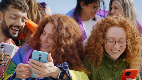 A community of LGBT people sitting using and looking at their mobile phones while sharing pictures with each other, smiling, gesticulating and having fun together outdoor photo