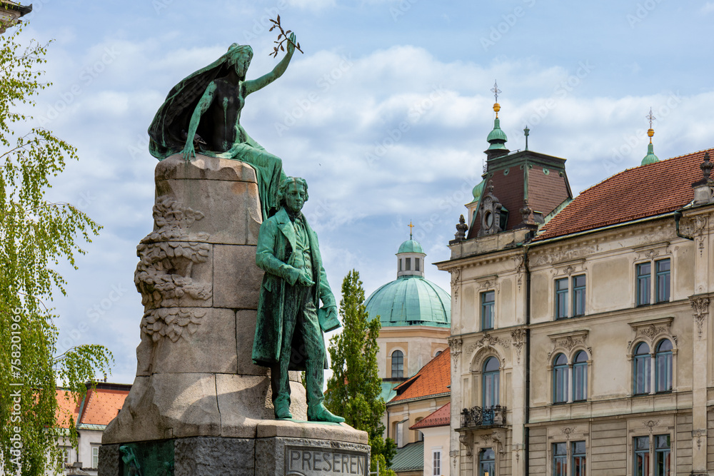 Ljubljana, Slovenia;  Saint Nicholas's Cathedral (Katedrala Sv. Nikolaj) and sculpture located in Prešeren square (Prešernov trg) in front of Franciscan Church of the Annunciation - obrazy, fototapety, plakaty 