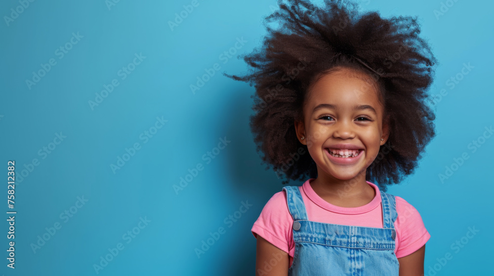 young African American girl with a big smile, wearing a pink shirt and a blue denim jumper, set against a light blue background young African American girl with a big smile, wearing a pink shirt and a blue denim jumper, set against a light blue background