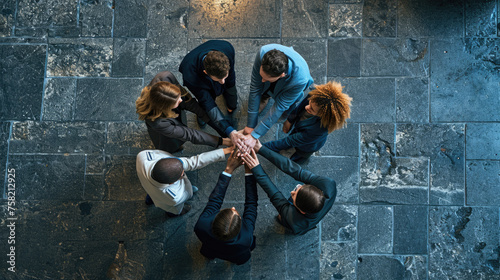 Overhead view of a diverse team of professionals huddled in a circle, placing their hands one on top of the other