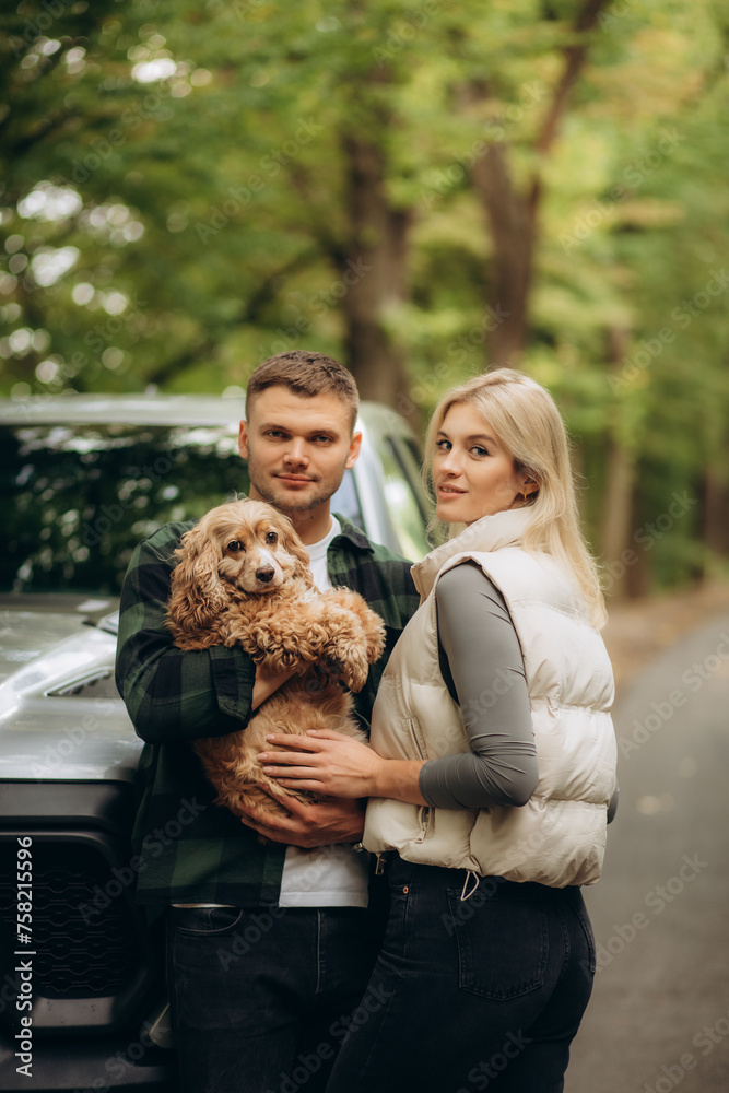 a happy young couple is traveling with a dog through the forest a happy young couple is traveling with a dog through the forest