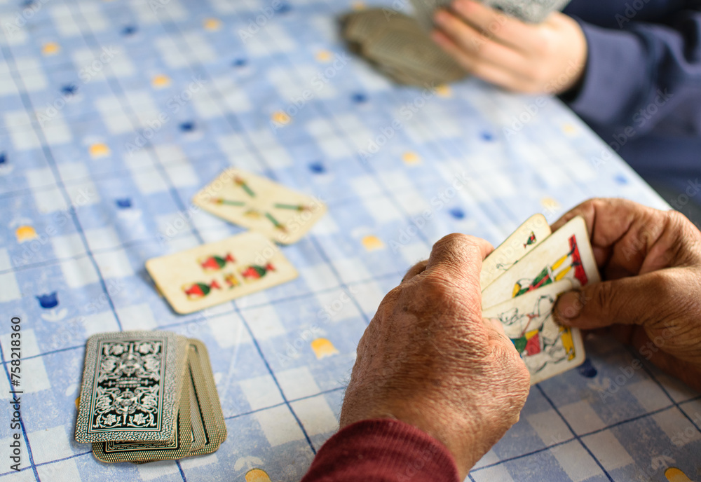 Fototapeta premium Elder hands playing cards on a blue table