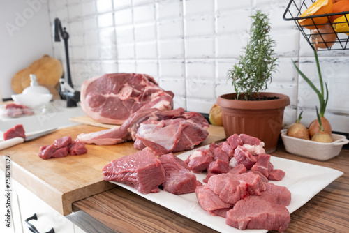 Different tipes of meat, cutting fresh raw meat on  board in white kitchen. Preparing pork meat, cooking photo