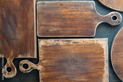 Three old retro cutting boards of various shapes on wooden background, closeup