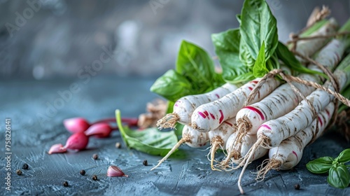  a group of white radishes with green leaves on top of them and other vegetables on a blue surface. photo