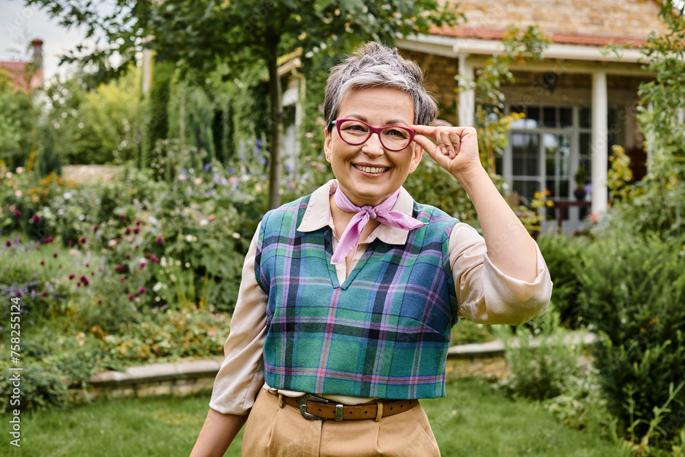 Obraz premium sophisticated mature joyful woman with short hair smiling at camera near her house in England
