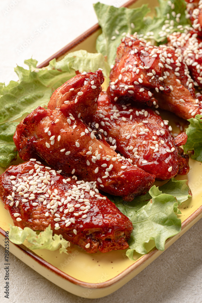 Obraz premium Portion of cooked chicken wings in sauce and sesame seeds