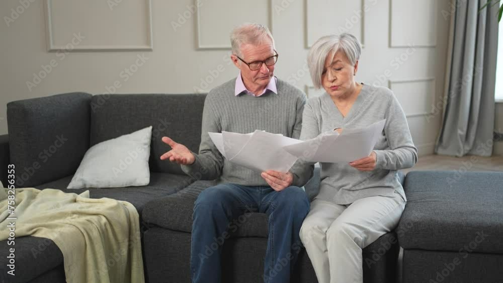Sad tired disappointed middle aged senior couple sit with paper document. Unhappy older mature man woman reading paper bill managing bank finances calculating taxes planning loan debt pension payment Sad tired disappointed middle aged senior couple sit with paper document. Unhappy older mature man woman reading paper bill managing bank finances calculating taxes planning loan debt pension payment