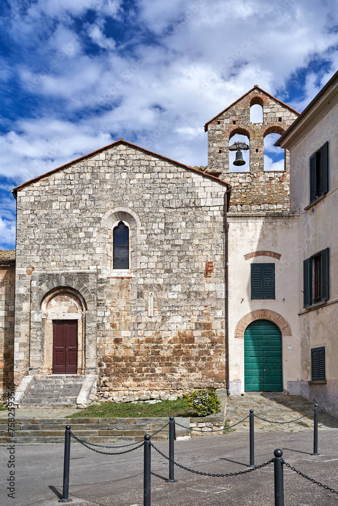 stone facade of a medieval church with a bell tower in the town of Magliano in Toscana