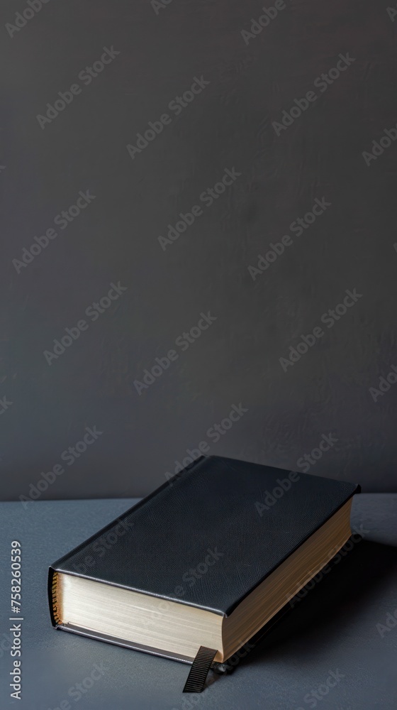 Black book on gray table and grey wall background. Black book on gray table and grey wall background.