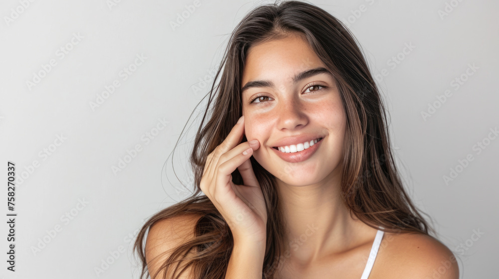 Smiling woman with a hand gently touching her face, displaying clear skin and a joyful expression. Smiling woman with a hand gently touching her face, displaying clear skin and a joyful expression.