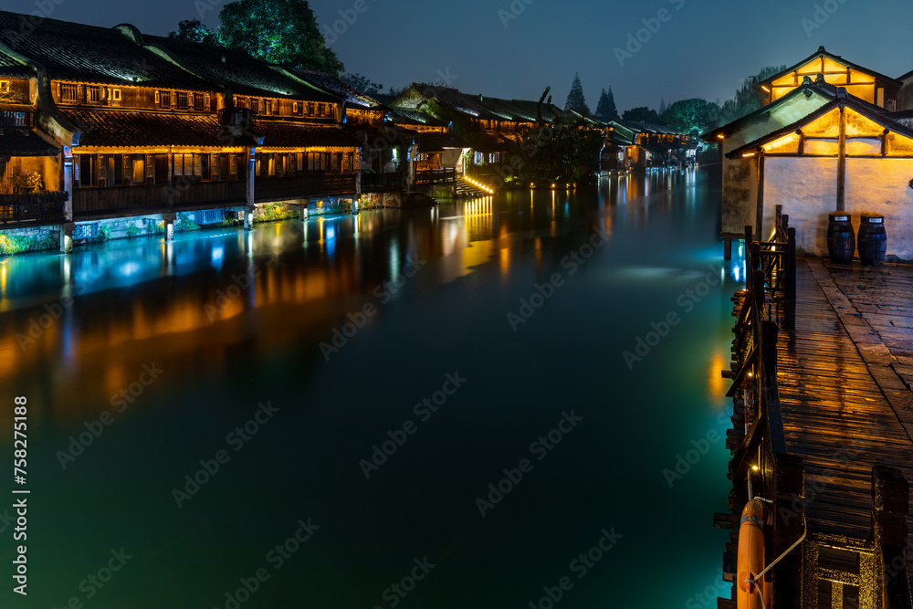 Attractive night scenery of traditional Chinese houses on both banks of a canal in a chilly and rainy evening at the ancient township of Wuzhen near Shanghai, China