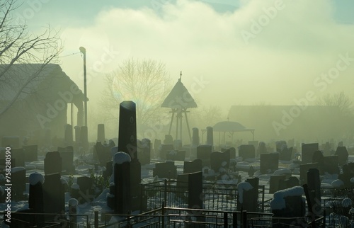 the old church, bell tower and cemetery in the morning winter fog