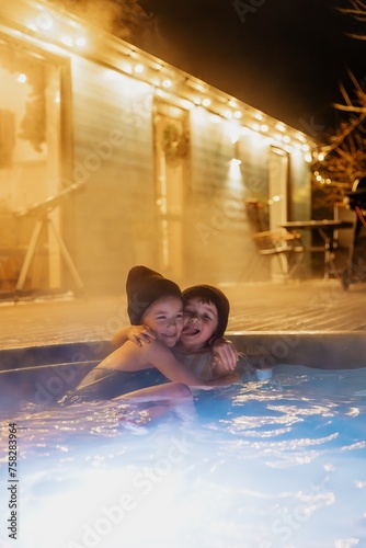 family vacation in a rented house with a hot tub (hot jacuzzi outside), children bathe in a hot tub outside in winter