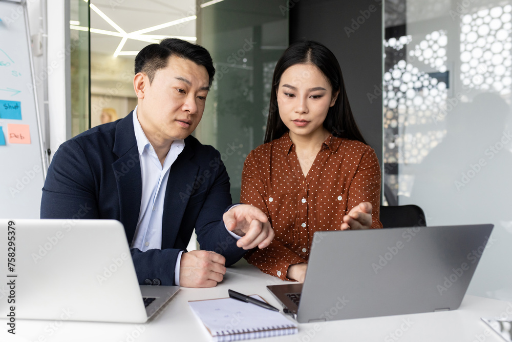 Two focused business colleagues working together on a laptop, engaged in a project discussion inside a modern office. Two focused business colleagues working together on a laptop, engaged in a project discussion inside a modern office.