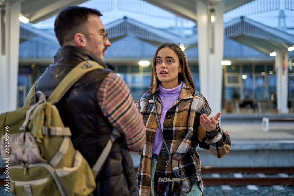 In the midst of travel, a couple engages in a serious conversation, trying to resolve an issue before their train departs.