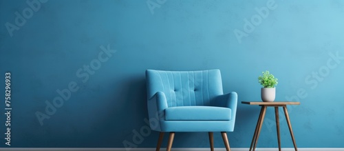 Blue chair in a room with grey walls and wooden floor with a table and shelf