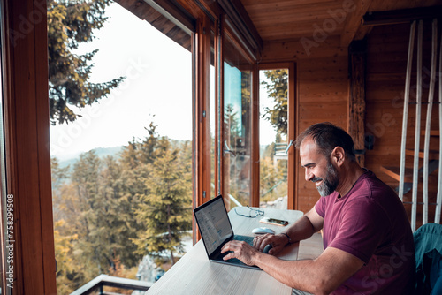 Man working on laptop in home with mountain view photo