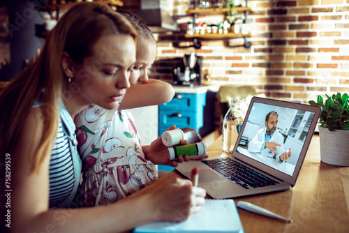 Concerned mother holding daughter and having video call with doctor from home