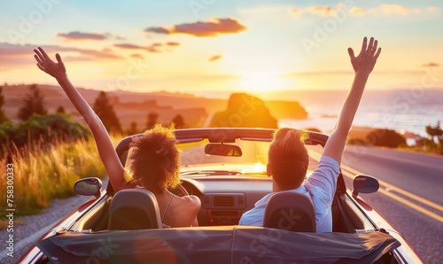 Romantic young couple enjoying their vacation driving a convertible car raising their arms to the sky