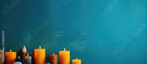 A collection of candles, some made of wax while others are electric blue fluidfilled, adorn a table against a serene blue wall at a special event near the horizon photo