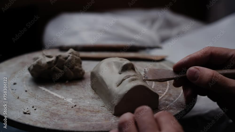 Close up of sculptor working on a clay mask on a pottery maker wheel in his atelier workshop studio