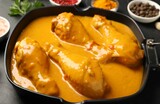 Tasty chicken curry and ingredients on black table, closeup