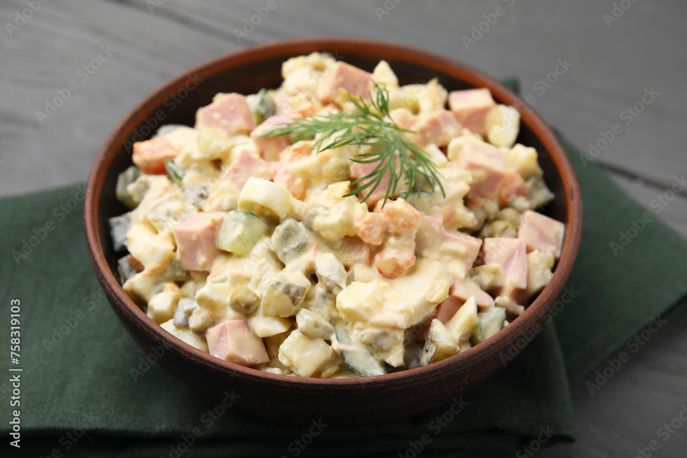 Tasty Olivier salad with boiled sausage in bowl on grey table, closeup Tasty Olivier salad with boiled sausage in bowl on grey table, closeup