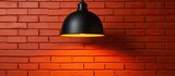 A black pendant light is suspended from a brick wall, creating a striking contrast between the dark metal fixture and the warm tones of the brickwork