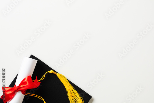 College graduation concept. Flat lay mortarboard cap with diploma on white background.
